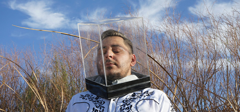 a man outside with a clear box over his head.