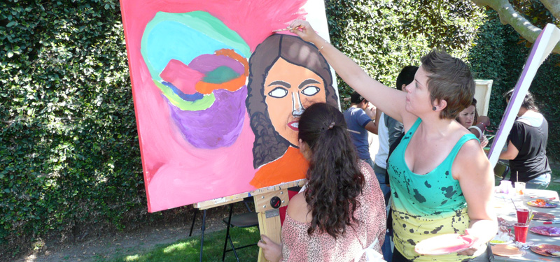 A group of people painting outside during a Summer Arts Workshop event.