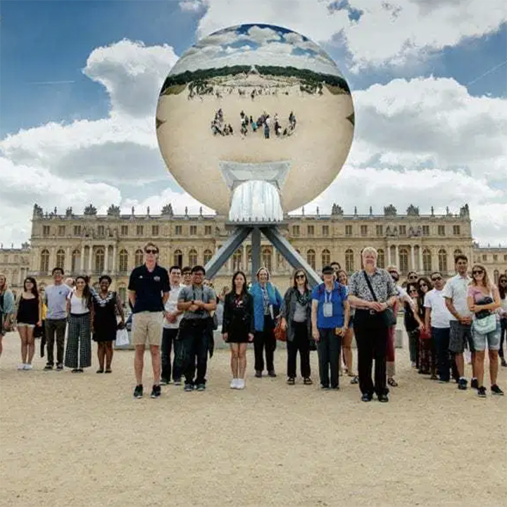 A choral group standing in front of a French palace
