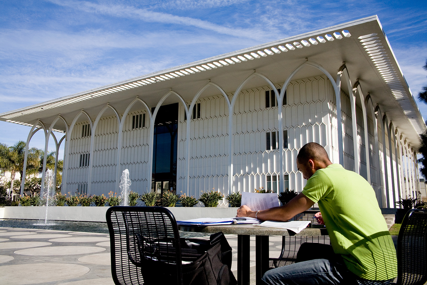 A student sitting at a table in front of an academic building