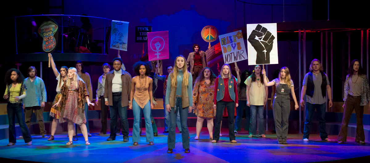 Students perform onstage in a production of Hair.