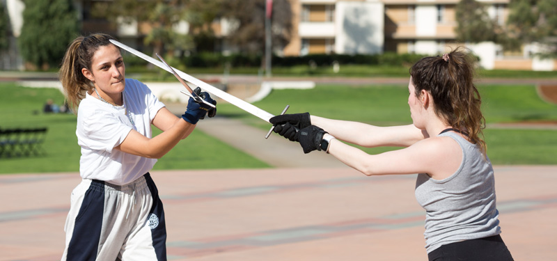 Two students practicing sword fighting in a Stage Combat class.