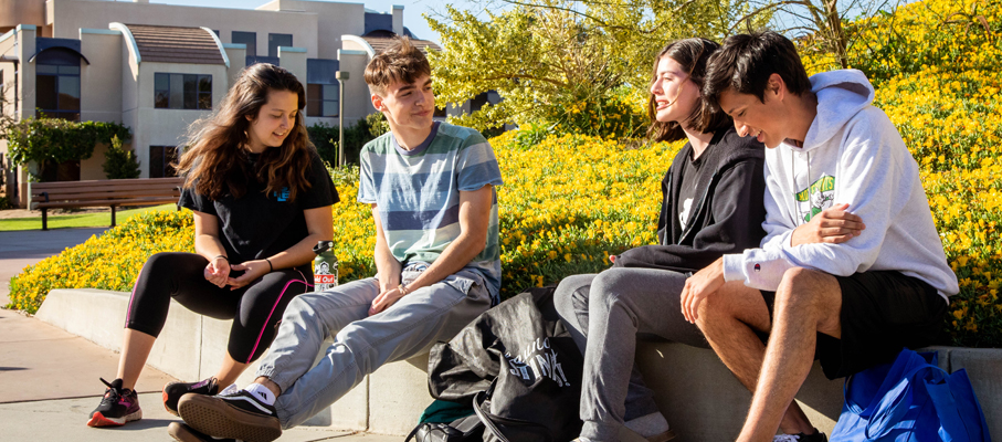 A group of students hanging out near the apartments on campus.