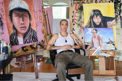 an artist sits in his studio in front of paintings