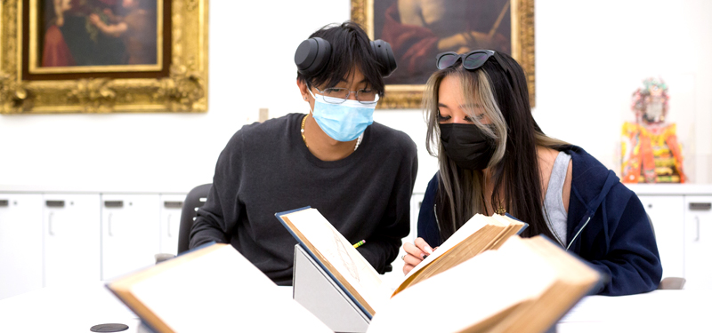 Two students examining a book for an art history class.