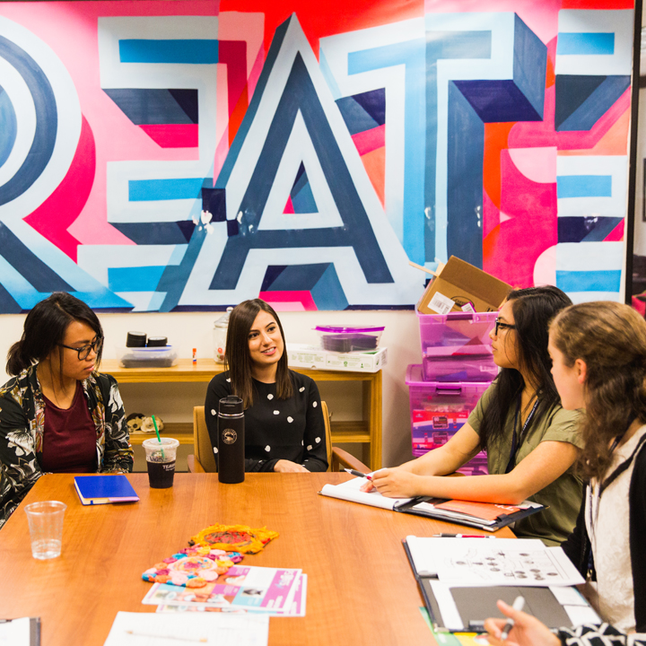 A group of students sitting in front of a large artwork.