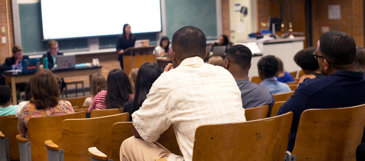 Students watching a debate in an auditorium.