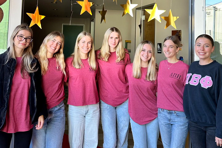 Lambda Pi Eta members in matching t-shirts pose for a photo.