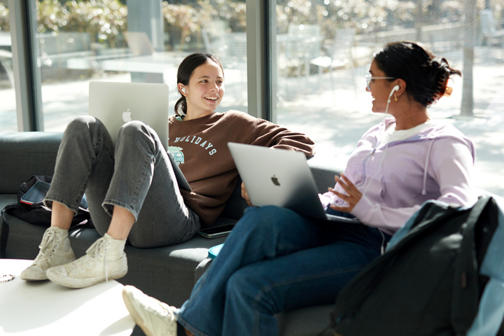 Two students chatting in a lounge area on campus.