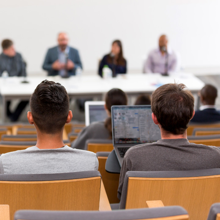 Students taking notes during a panel discussion.