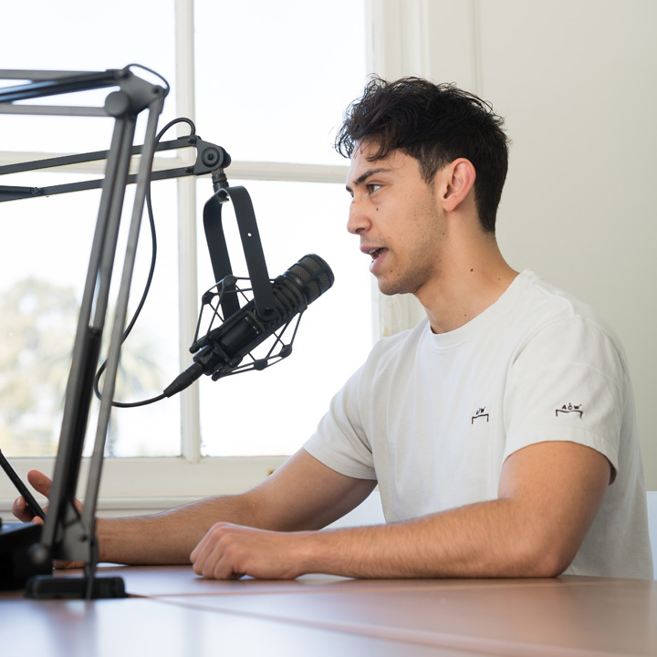 A student speaking into a microphone inside the podcasting studio.