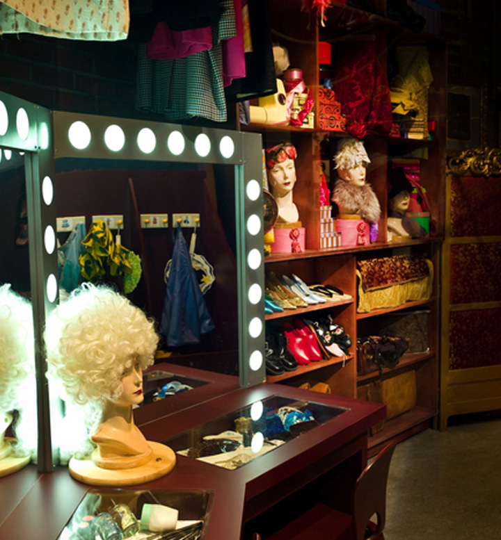 A collection of wigs and outfits in a dressing room.