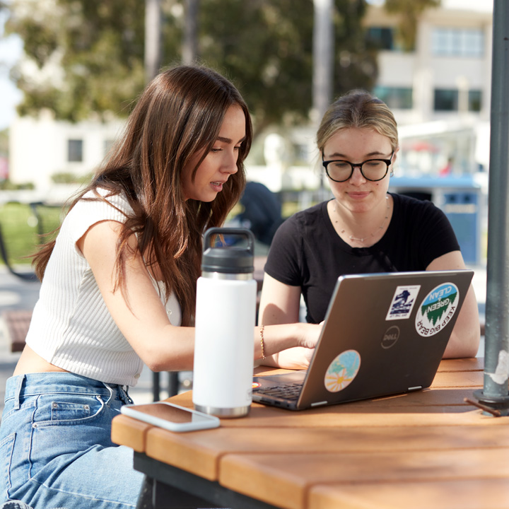 Two students looking at a laptop by the Foley building.