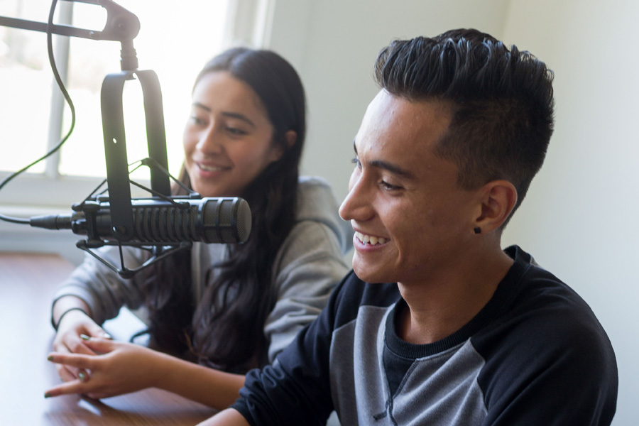 Two students in a studio, recording a podcast.