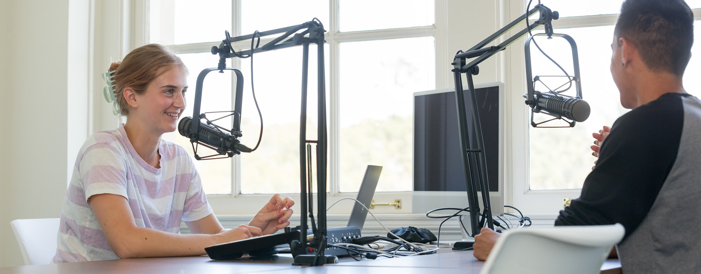Students recording an episode of a podcast in a studio.