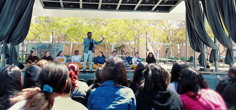 A man addressing the audience at a dance event taking place at the Drollinger Family Stage.