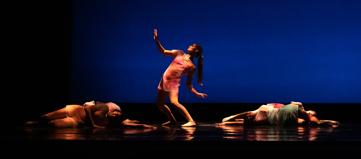 One dancer standing among others on the floor.