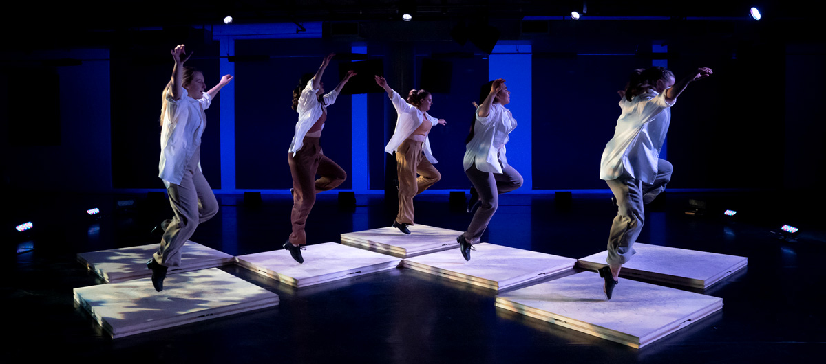 A group of dancers performing on top of white squares.