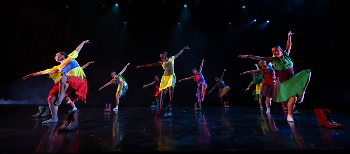 Dancers in colorful outfits performing onstage during the Fall Dance Concert.
