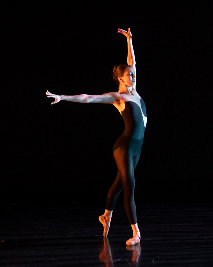 A dancer in black extending her arms.