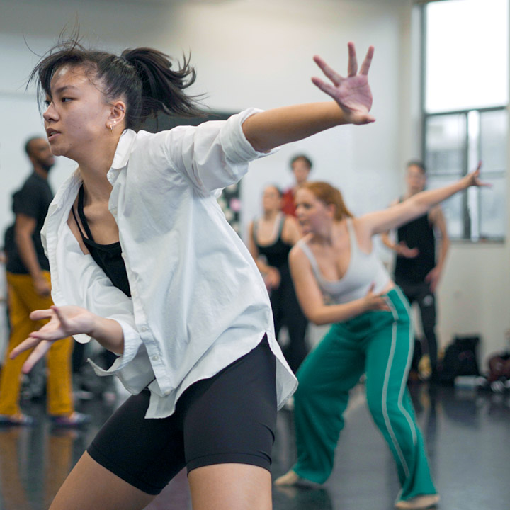 Dancers in a studio performing while others watch.