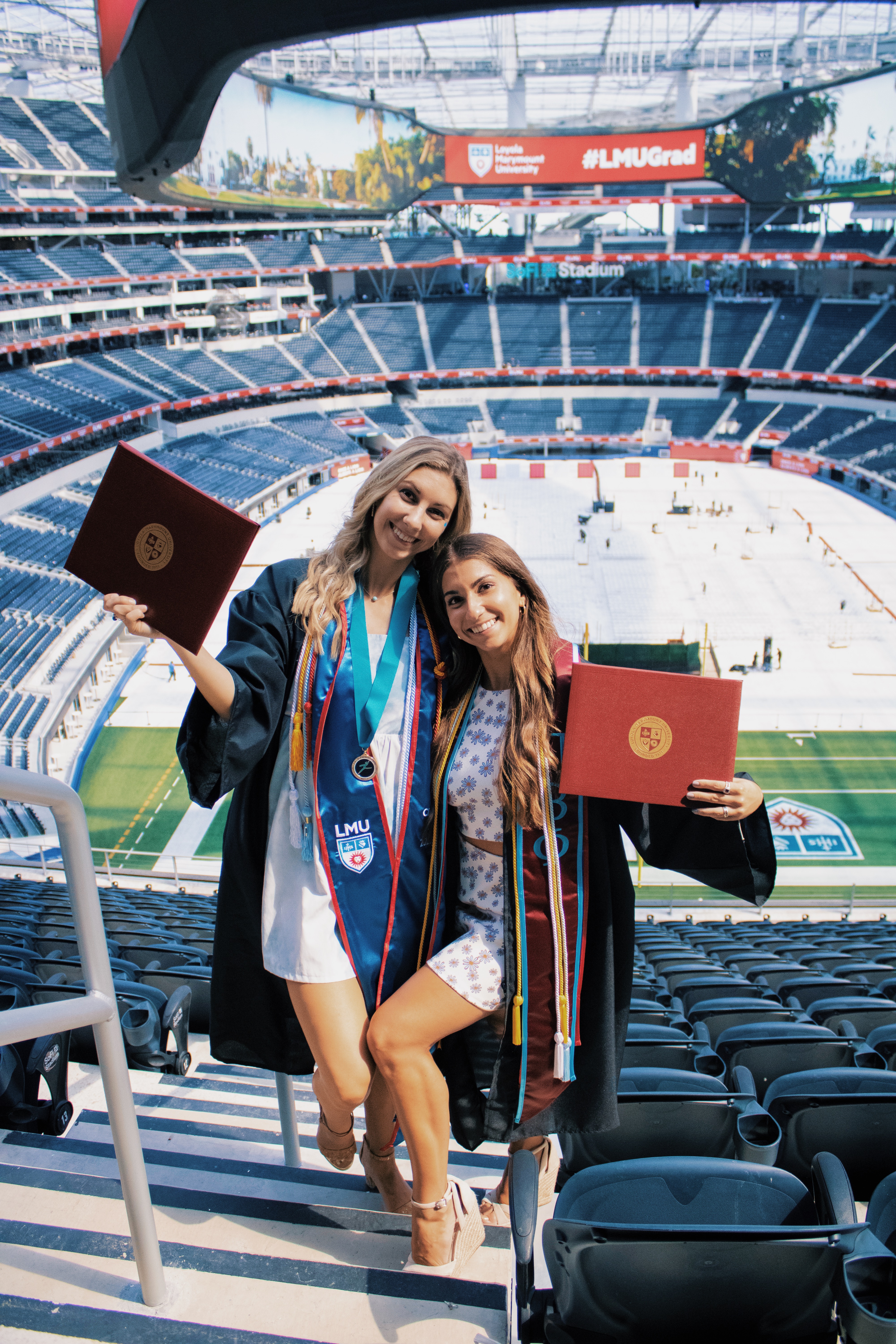 Two dance major graduates holding diplomas