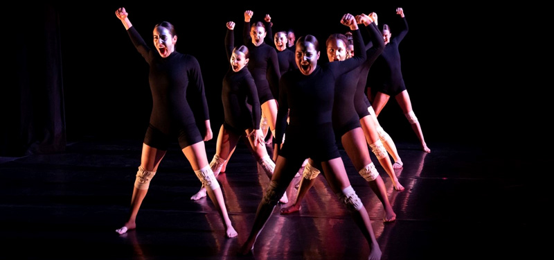 Dancers standing in formation with an intense look.
