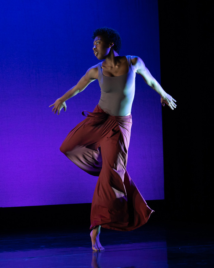 A dancer performs in front of an indigo background.