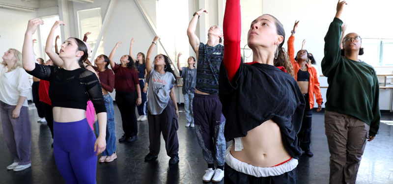 A large group of dancers practicing in a studio.