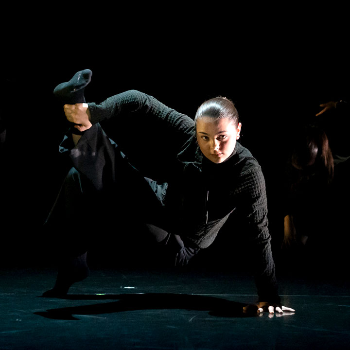 A dancer in black performing during a concert.