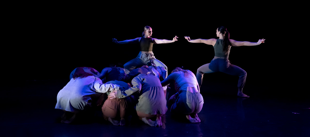 Dancers crouching near two others onstage in Strub Theatre.
