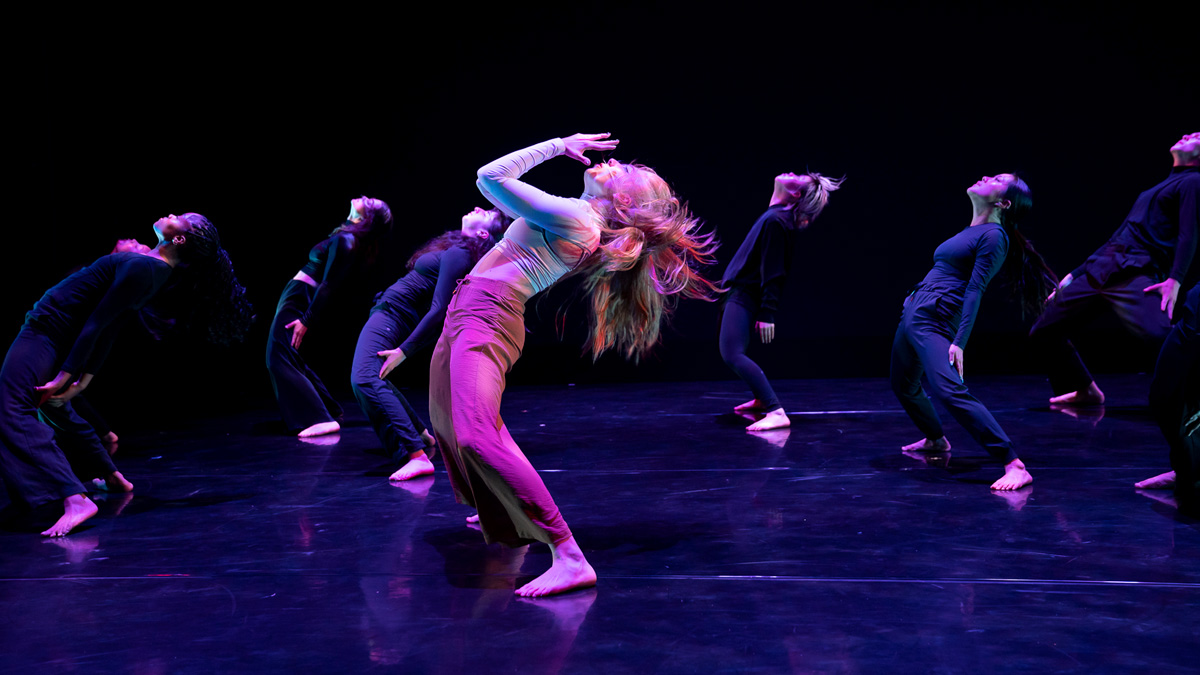 A group of dancers leaning back during a performance/