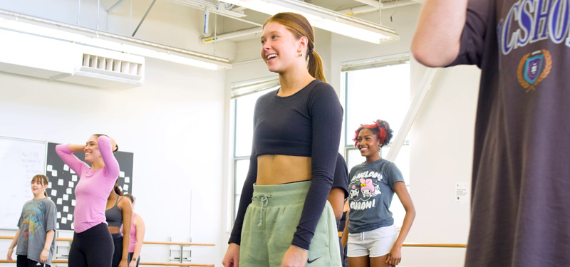 Dance students smiling while working in a studio.