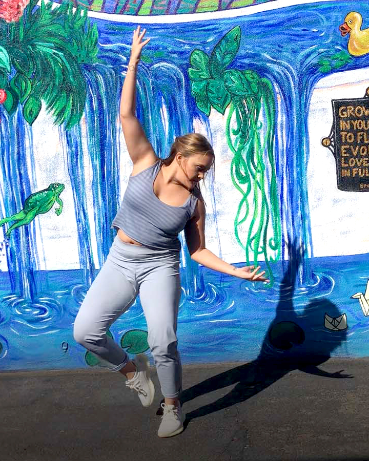 Dancer performs in front of a mural.