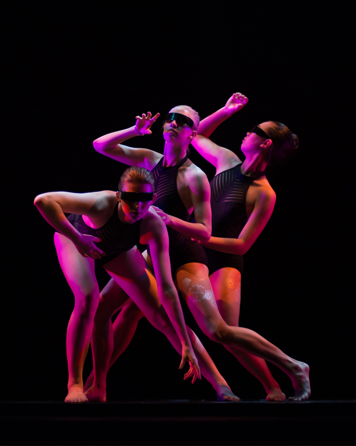 Three dancers perform in front of dark background at Spring '17 Student Concert.