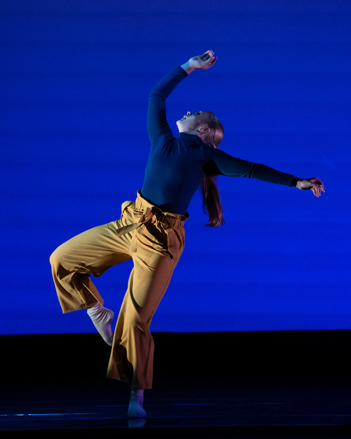 Dancer performing in front of a blue background at the Fall 2021 Faculty Concert.