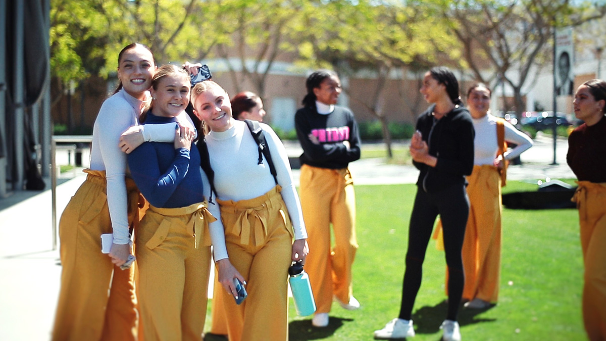 Three dancers smile for a photo at the Drollinger Family Stage.