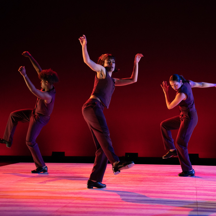 Three dancers illuminated in red.