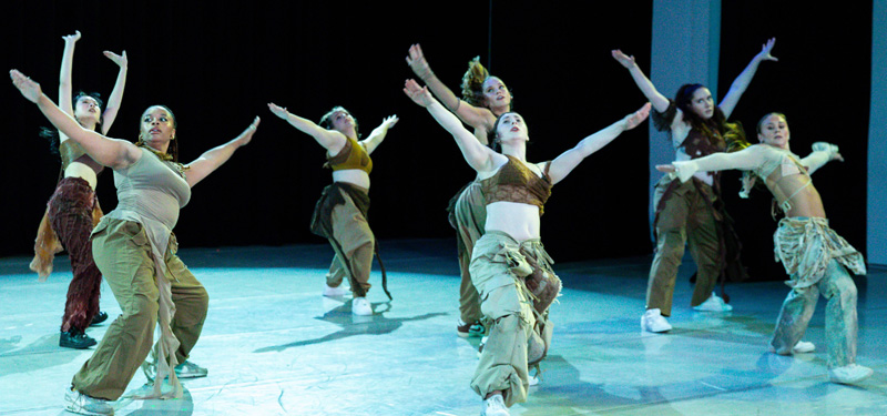 A group of dancers leaning to the side with their arms raised.