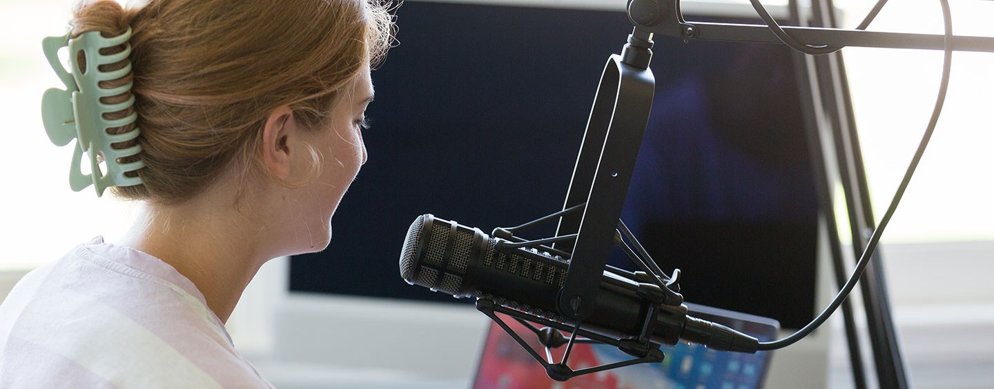 A student speaking into a professional microphone in recording studio