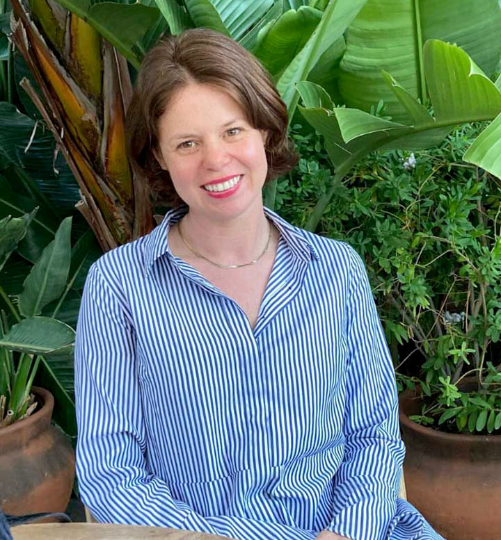 A photo of Corrina Laughlin sitting next to plants.