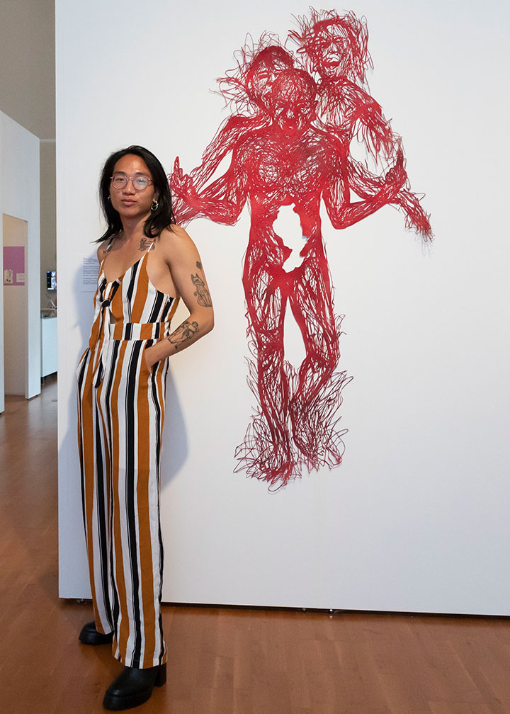 Featured artist standing next to one of their pieces