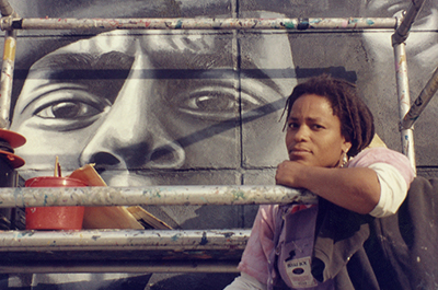 Artist Noni Olabisi in front of their mural