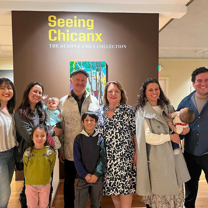 A group of people posing for a photo in front of Seeing Chicanx signage.
