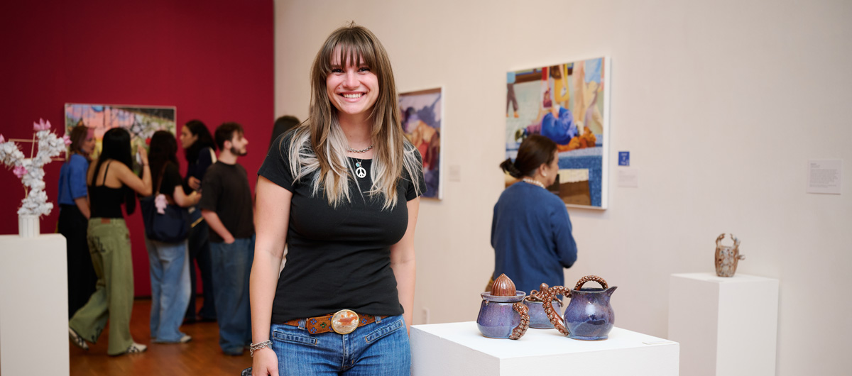 A woman standing next to her sculpture on display at the exhibition.