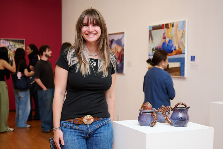 A woman standing with her sculpture at the Young Contemporaries 2026 exhibition.
