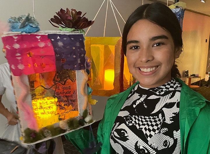 A student holding up a decorated art piece