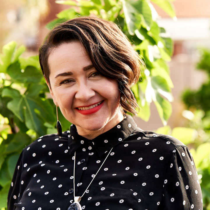 Photo of Berenice Badillo, wearing black and sitting outside.