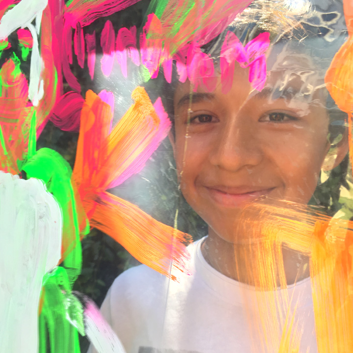 A kid peeking through artwork during a workshop event.