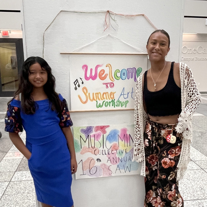 Two people standing in front of artwork at Summer Arts Workshop.